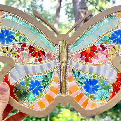 Colorful mosaic butterfly with a hand holding it against a natural background