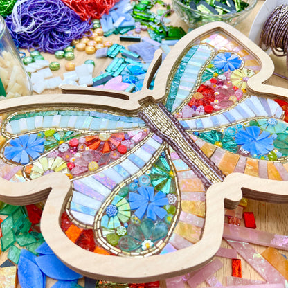 Mosaic butterfly craft with colorful beads and tiles on a wooden base