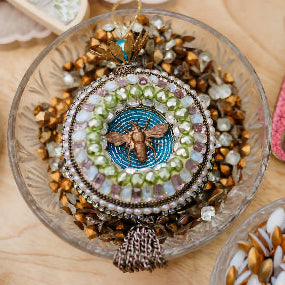 Decorative items including a mosaic owl, beehive-shaped box, and colorful card on a wooden surface.