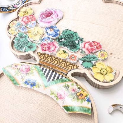 A charming floral mosaic in progress using a curated collection of vintage china patterns set inside a custom bouquet-in-a-vase wooden frame.