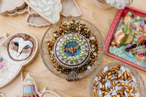 Decorative items including a glass bowl with beadwork and a colorful card on a wooden surface.