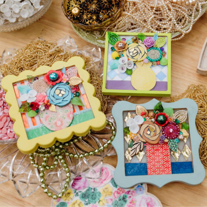Decorative picture frames with floral designs on a wooden surface.